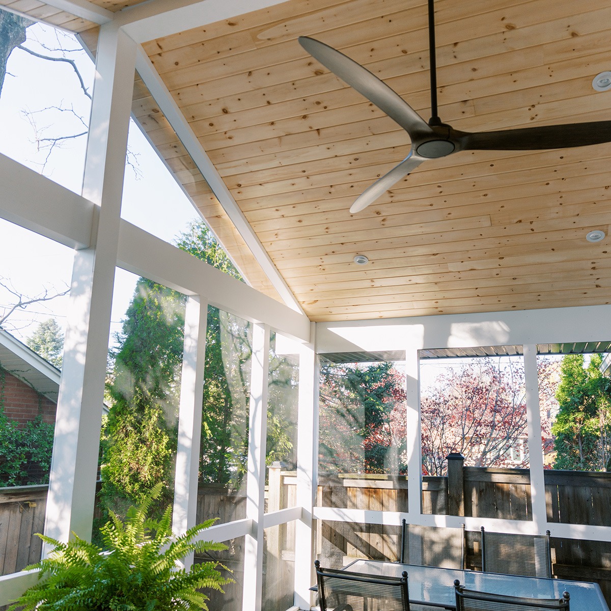The inside of a screen deck room focused on the stylish ceiling fan and wooden ceiling.